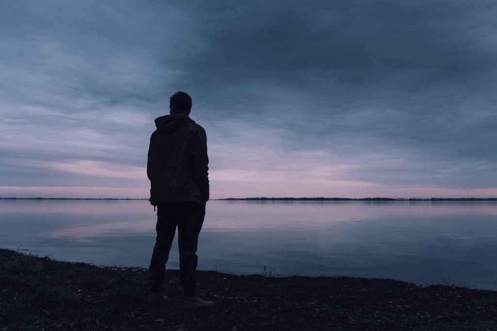 man looking across a lake