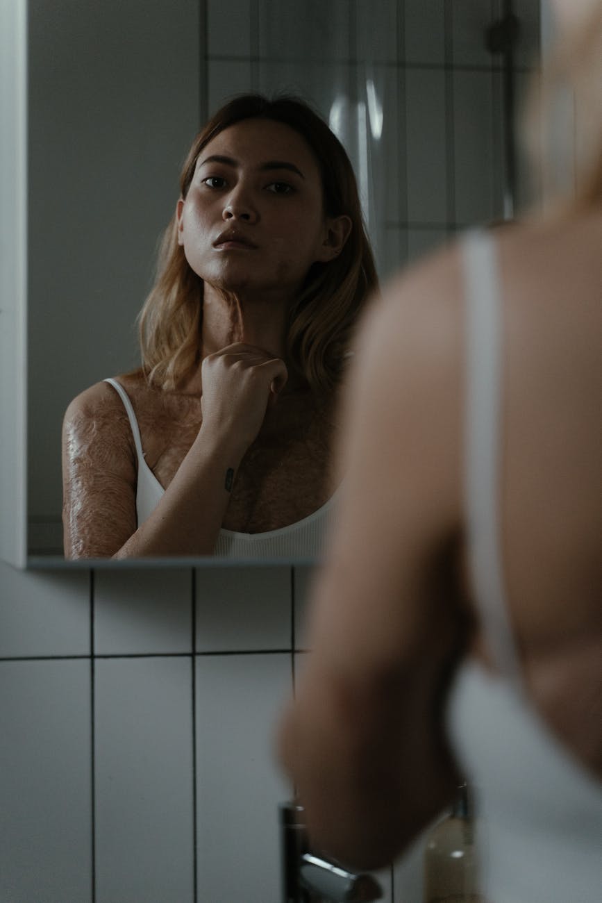 a woman with scars on her body looking at a mirror